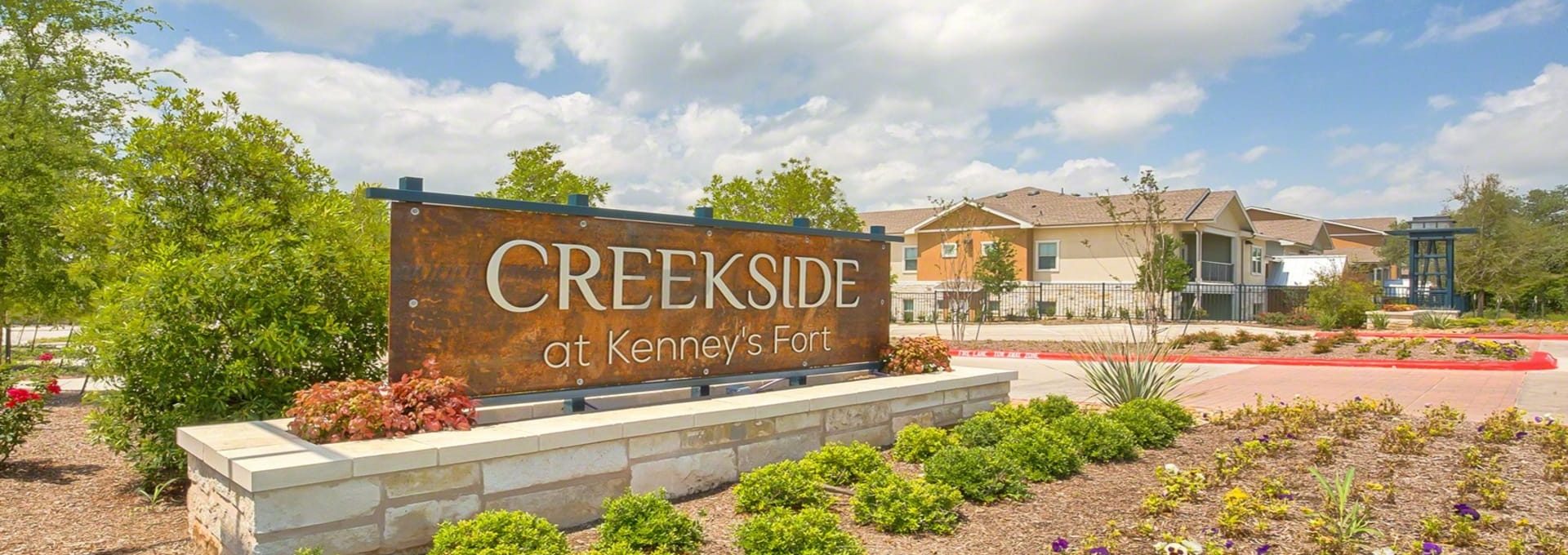 the sign for creekside apartments in the middle of a field at The Creekside at Kenneys Fort