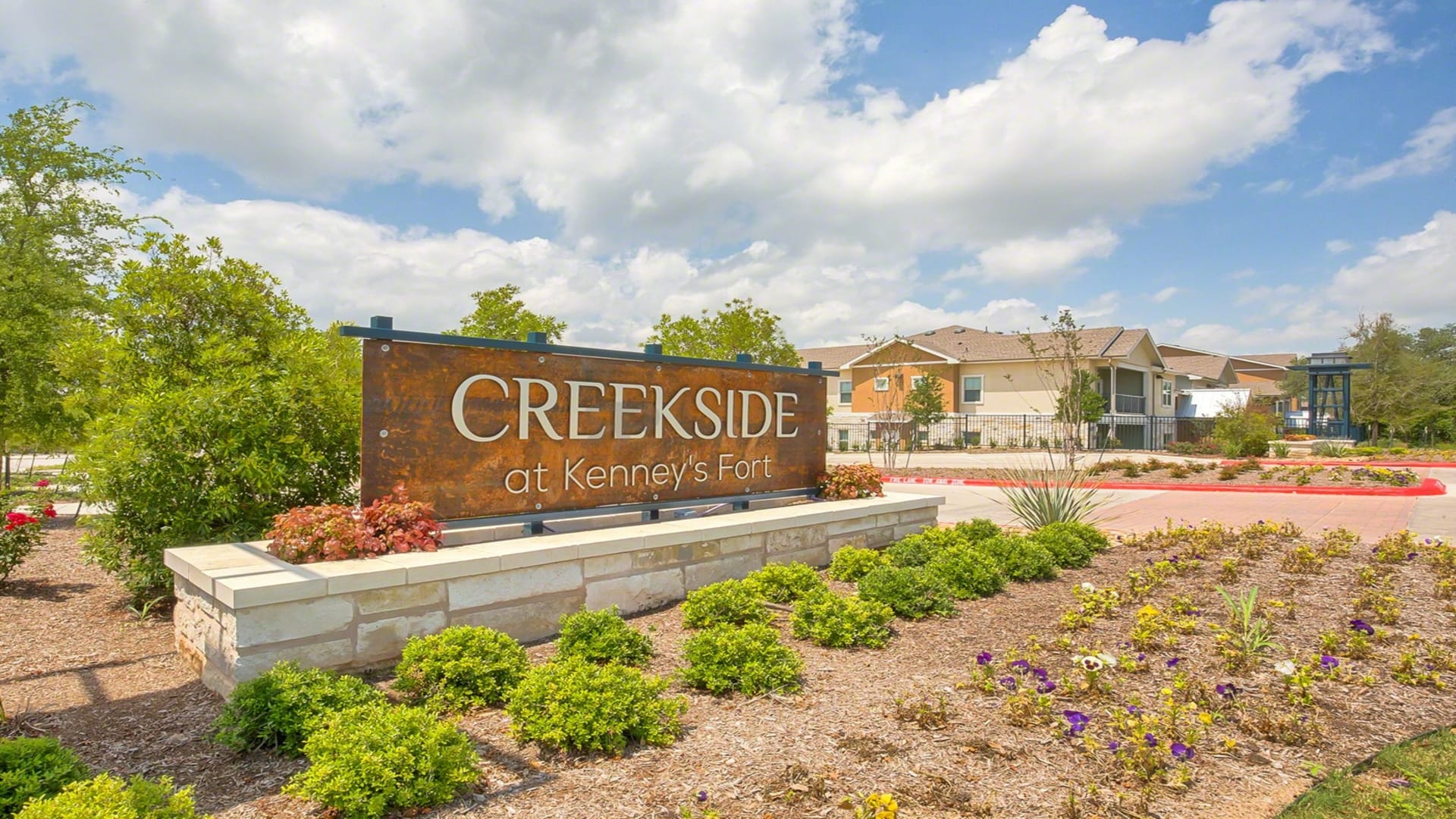 the sign for creekside apartments in the middle of a field at The Creekside at Kenneys Fort