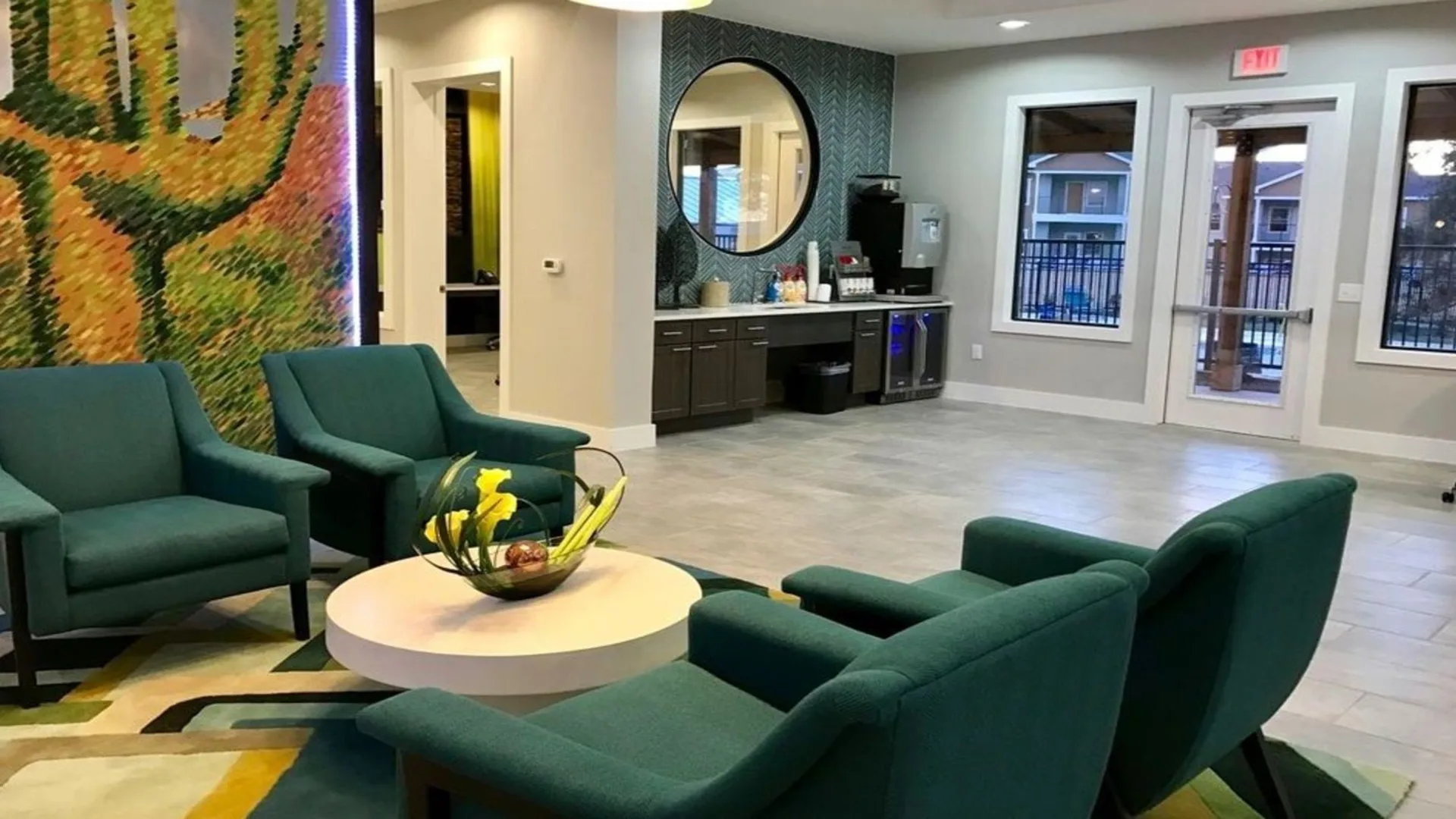 a lobby with green chairs and a large mural at The Creekside at Kenneys Fort