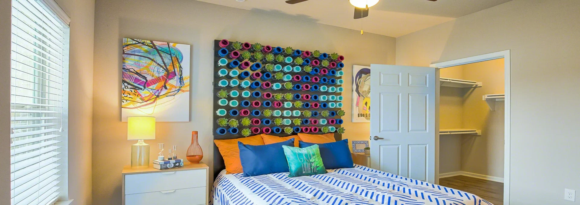 a bedroom with a colorful bedspread and a ceiling fan at The Creekside at Kenneys Fort